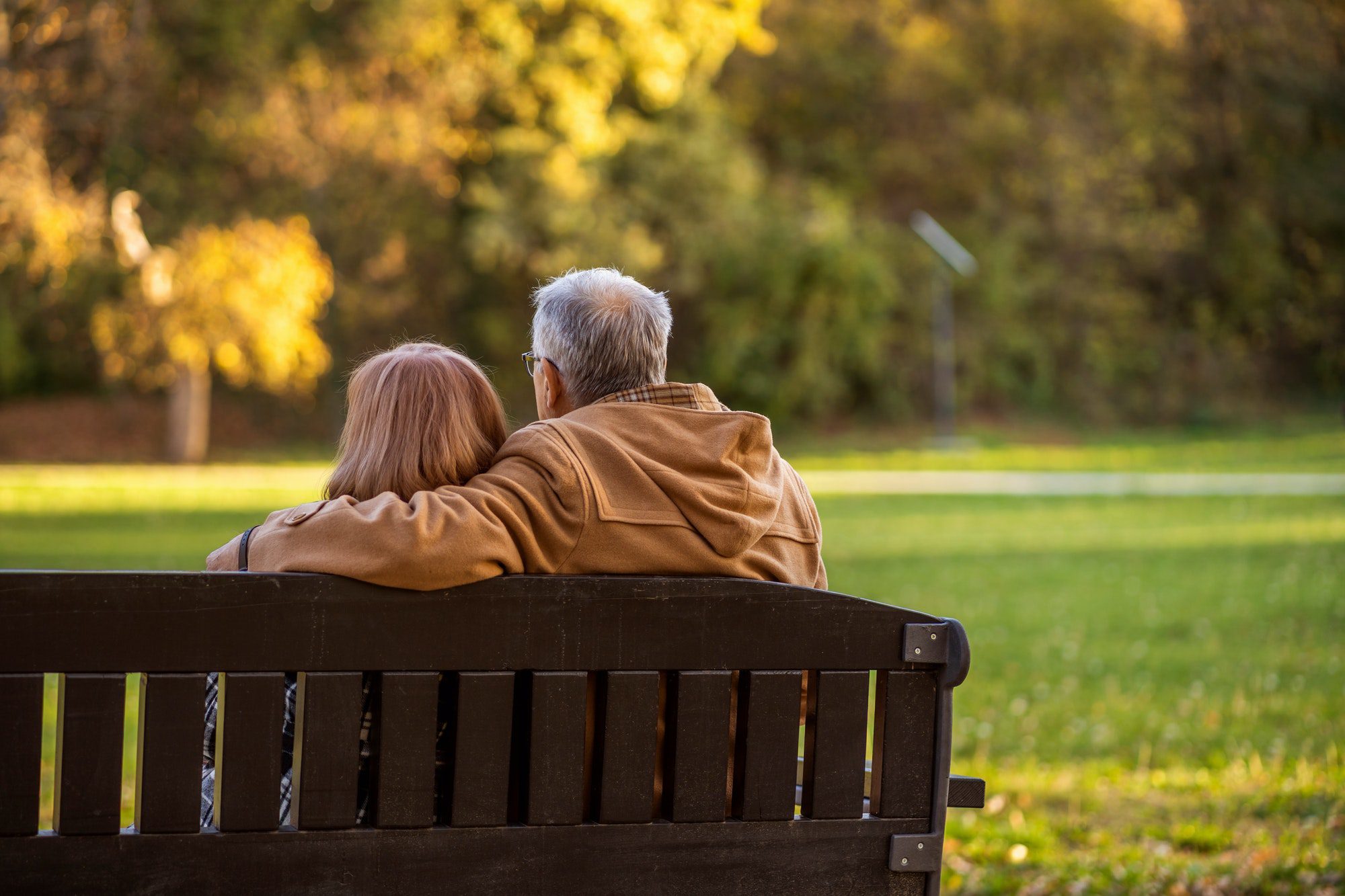 Senior couple in the park sitting on a bench as they discuss Medicare Advantage Plans