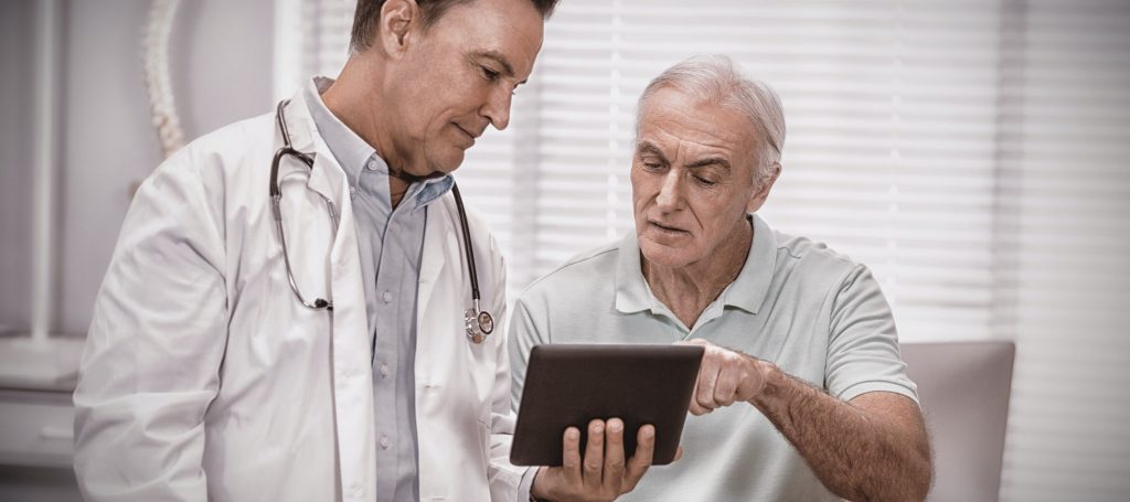 Doctor and senior patient using digital tablet to discuss medicare.